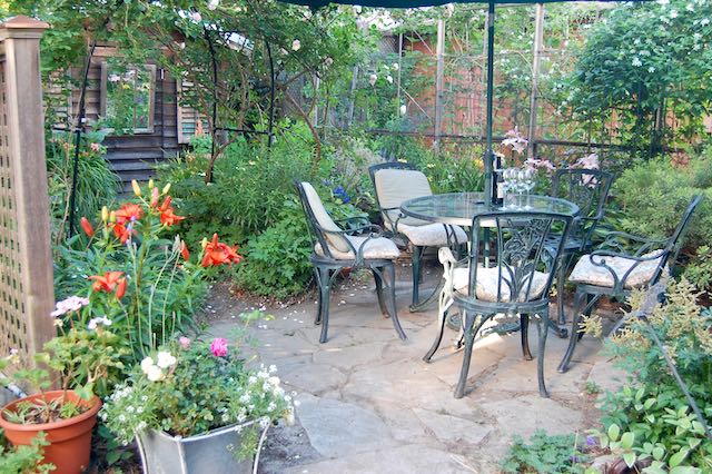 Small patio with round table and crazy paving surrounded by plants