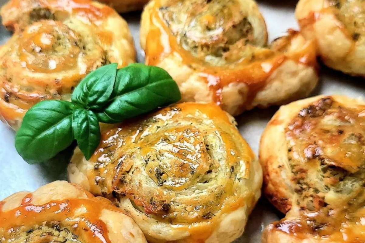 Italian cheesy garlic rolls with basil leaves on a baking sheet, perfect for appetizers.