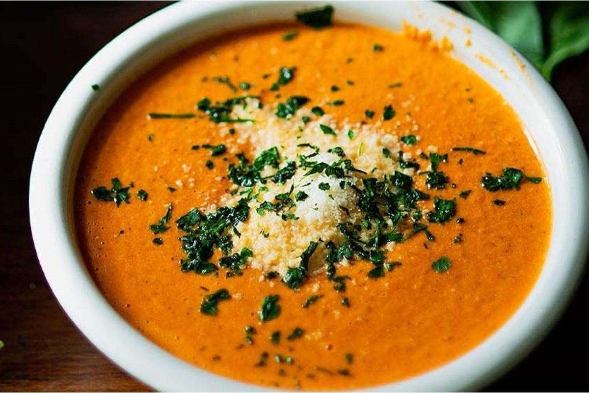 A bowl of vegetable soup with parmesan cheese and parsley.
