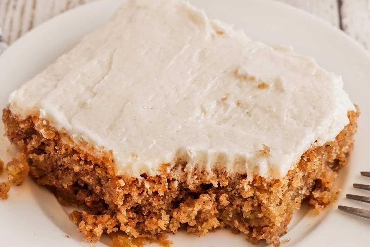 A slice of moist carrot cake sits elegantly on a white plate.